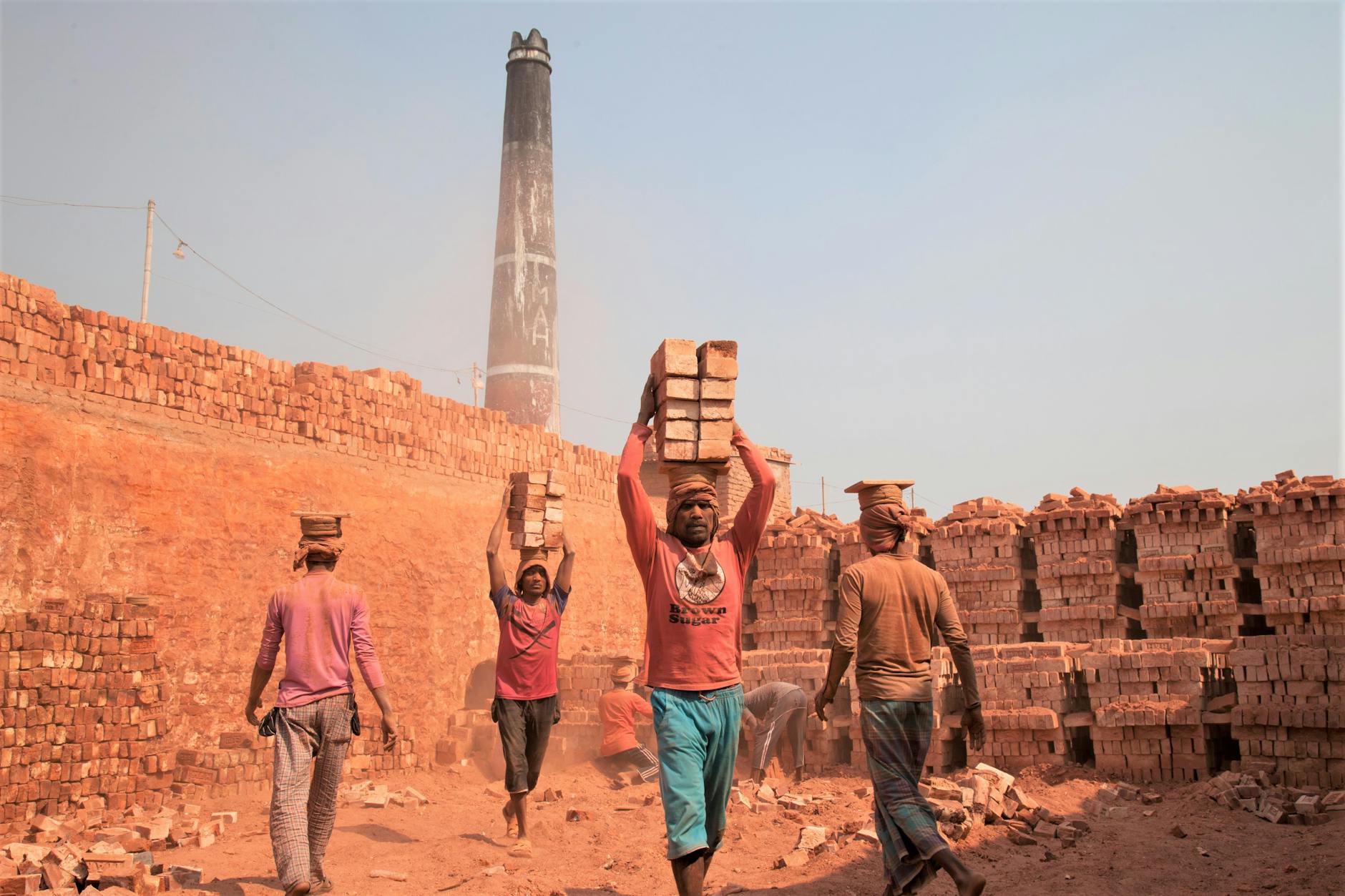 Workers carrying bricks at a construction site in Gabtoli, showcasing manual labor.